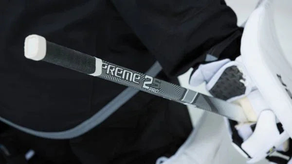 Close-up of Bauer Supreme 2S Pro hockey stick held by goalie in black and white gear at The Hockey Shop