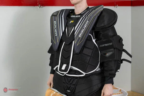 Bauer Supreme 1S goalie chest protector worn in hockey locker room at TheHockeyShop.com