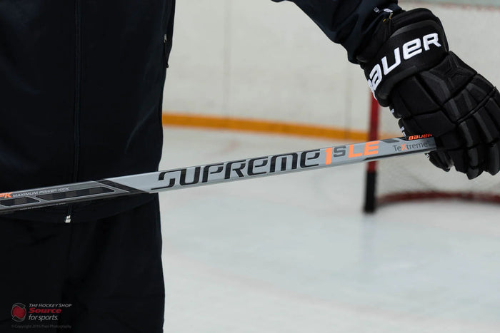 Bauer Supreme 1S LE hockey stick held by player in Bauer gloves on ice rink at The Hockey Shop