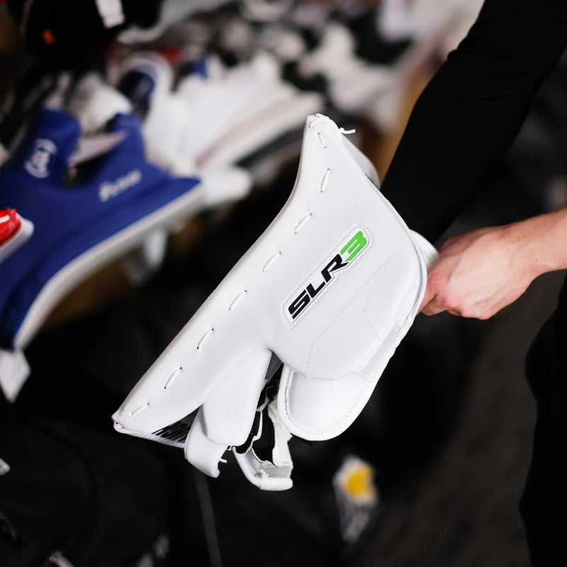 Person holding white SLR3 hockey goalie blocker at The Hockey Shop equipment display