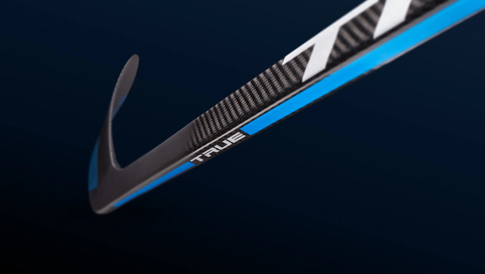 Close-up of a TRUE carbon fiber hockey stick blade with blue accents on dark background.