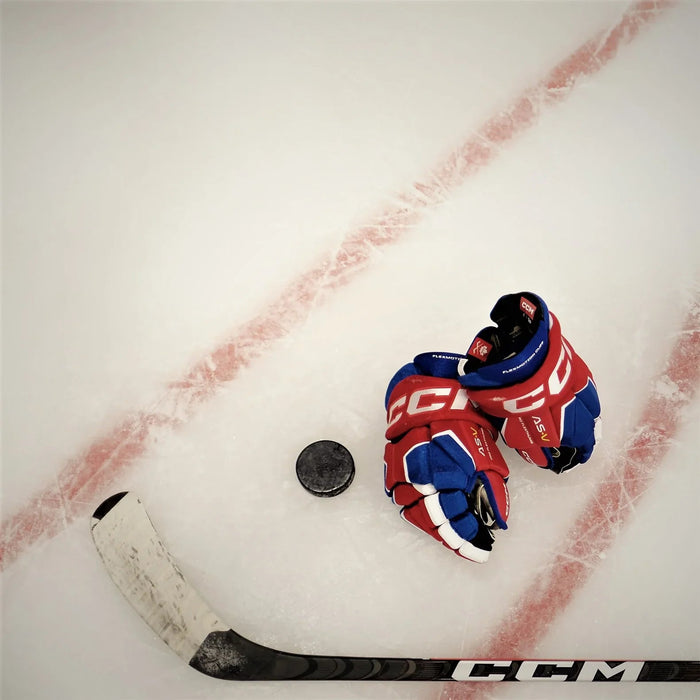 CCM hockey gloves, stick, and puck on ice rink at The Hockey Shop