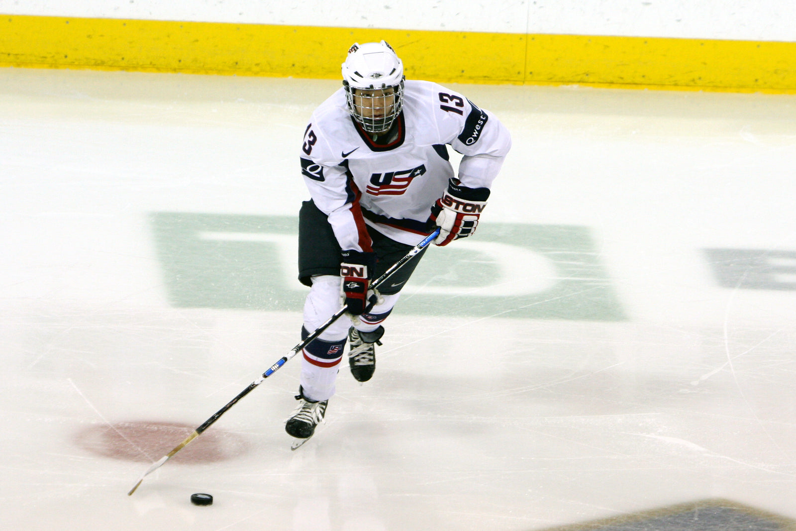 Julie Chu skating with the puck in her Team USA jersey