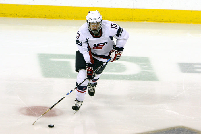 Julie Chu skating with the puck in her Team USA jersey