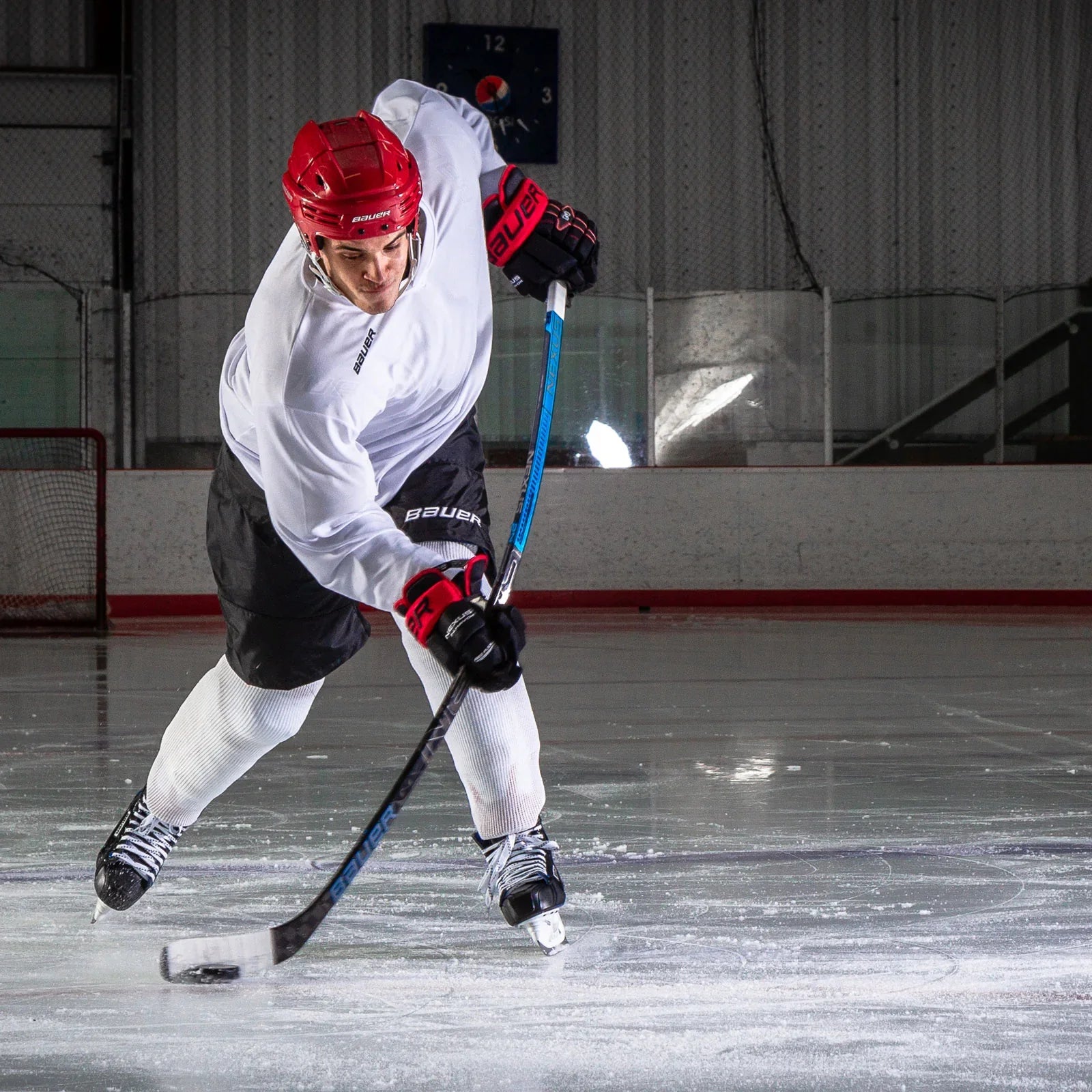 Hockey player in Bauer gear taking a slapshot on ice rink at The Hockey Shop