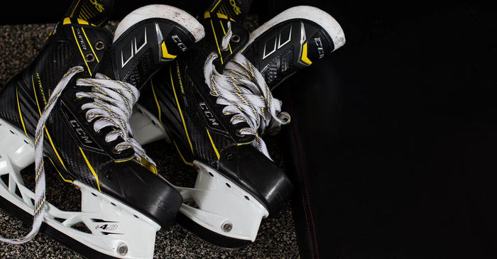 Pair of black and yellow CCM hockey skates on locker room floor at The Hockey Shop