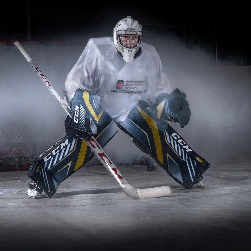 Hockey goalie in full CCM gear with stick, pads, and helmet, posing on ice for The Hockey Shop