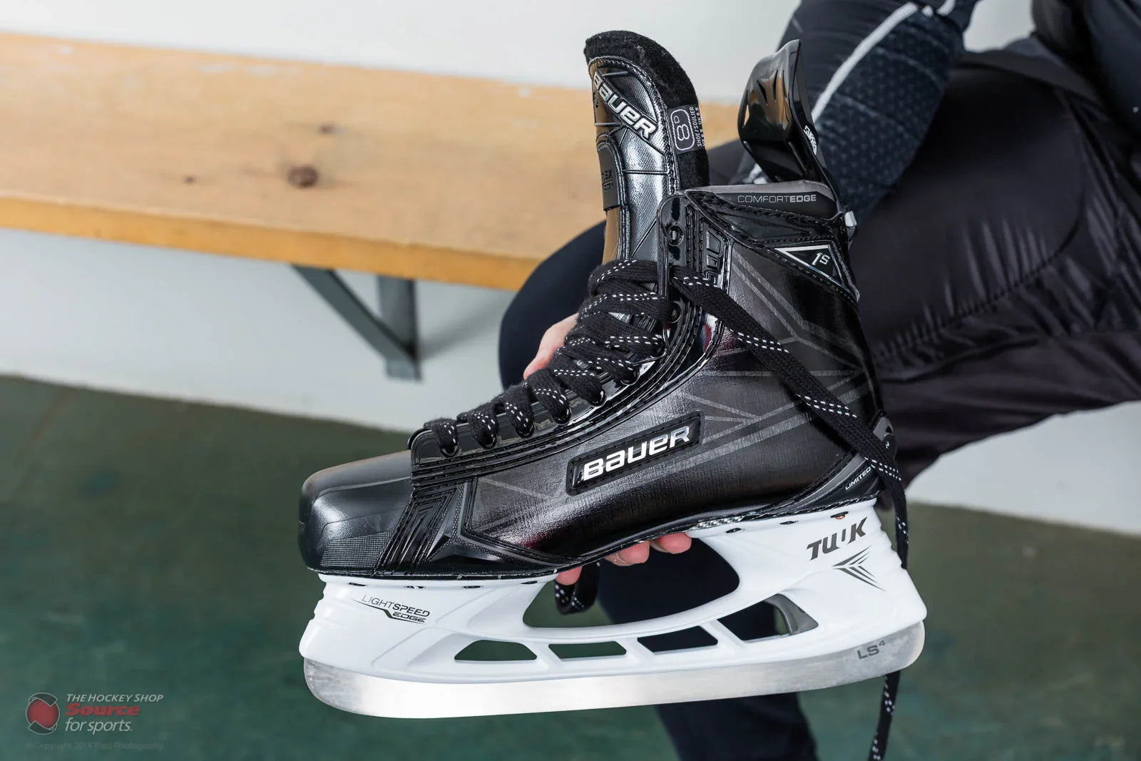 Bauer 1S LE hockey skate with TUUK Lightspeed blade, held in locker room at TheHockeyShop.com