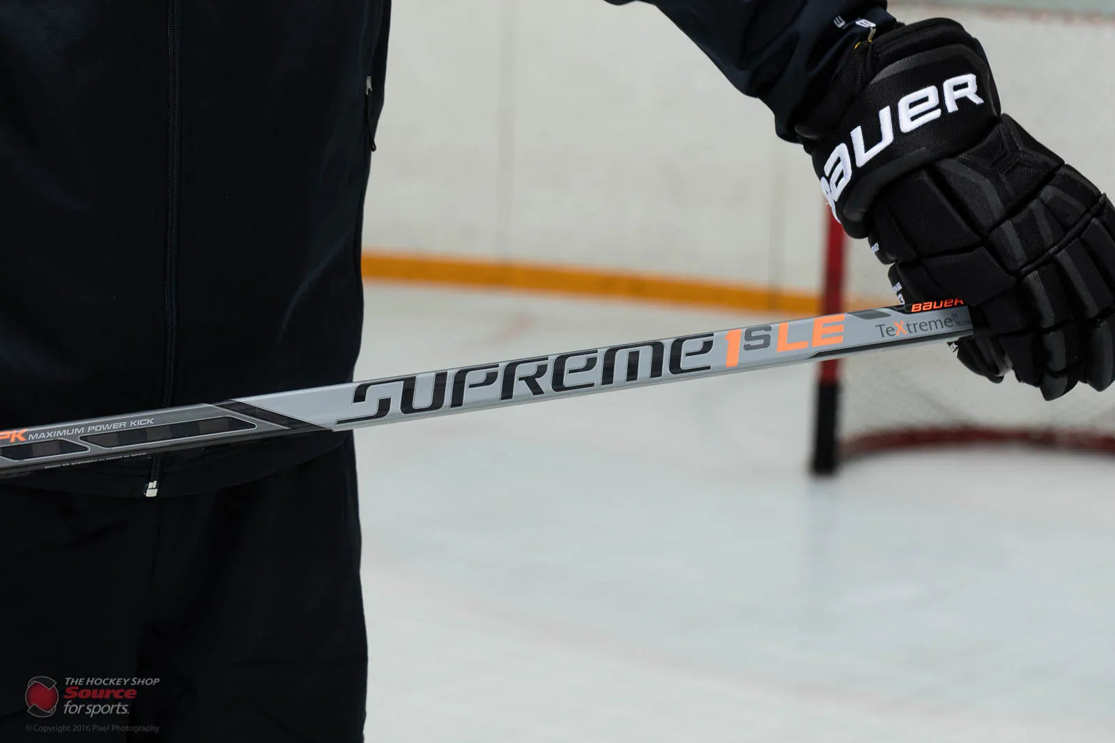 Bauer Supreme 1S LE hockey stick held by player in Bauer gloves on ice rink at The Hockey Shop