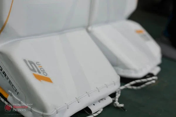 Close-up of Bauer 1S Odin goalie leg pads at The Hockey Shop, white with yellow accents