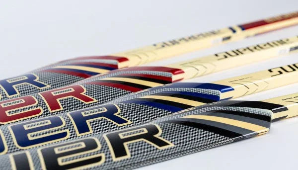 Bauer Supreme hockey sticks with red, blue, and gold accents at The Hockey Shop