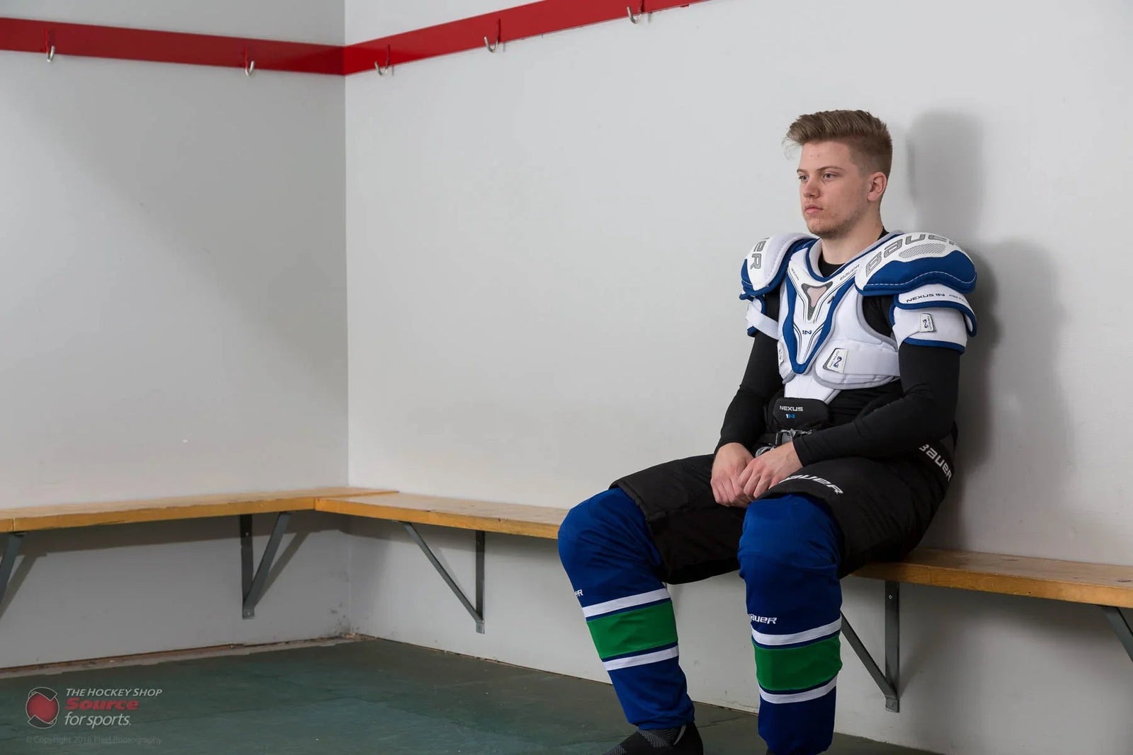 Hockey player in Bauer Nexus shoulder pads sitting in locker room at The Hockey Shop