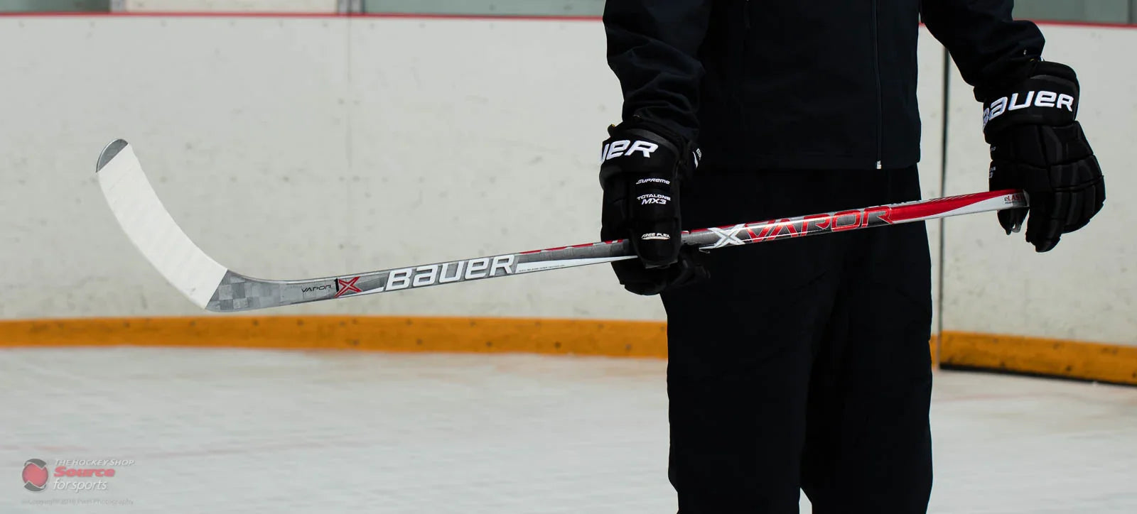 Bauer Vapor 1X hockey stick held on ice rink, hockey gloves, The Hockey Shop equipment