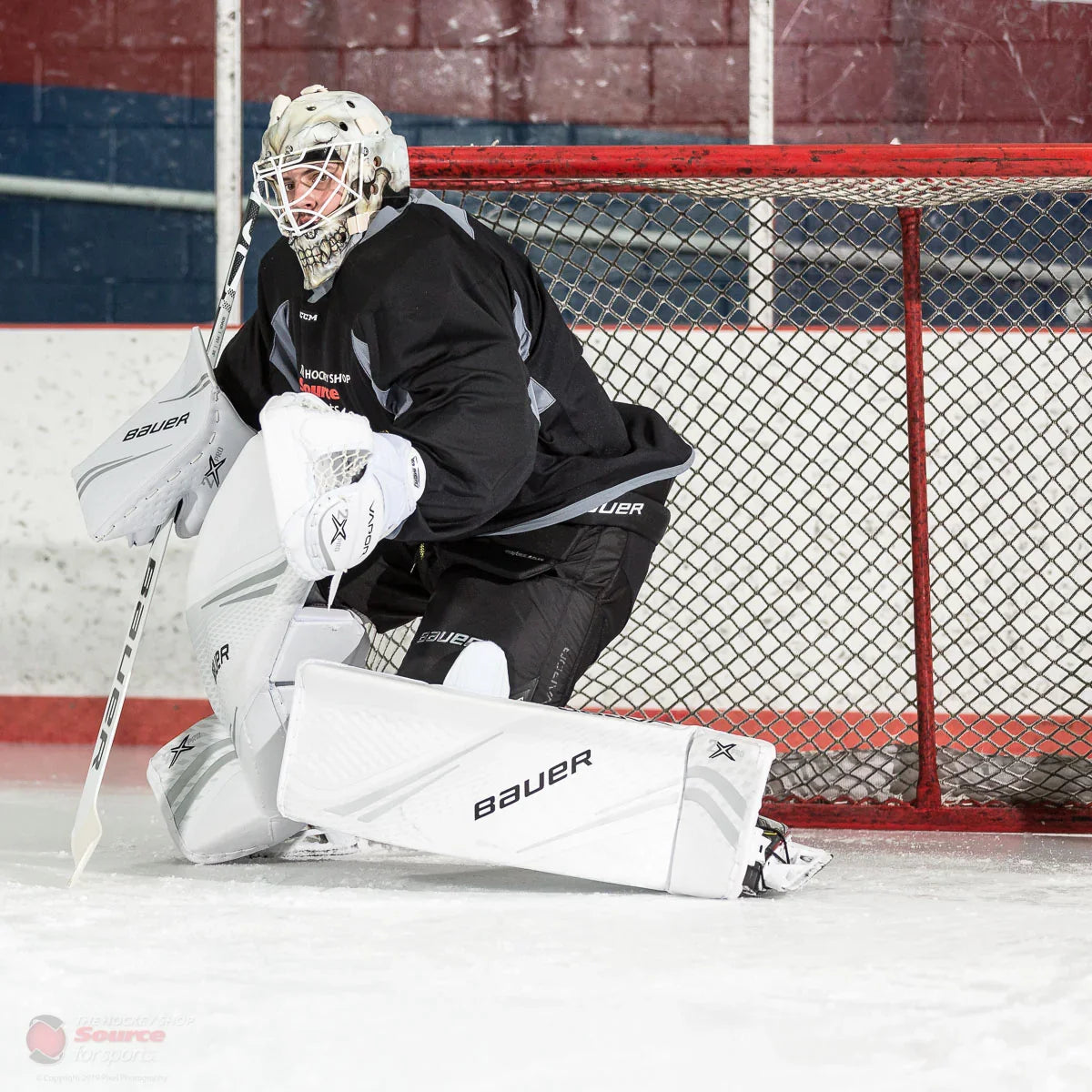 Ice hockey goalie in Bauer Vapor 2X Pro goalie gear guarding net at rink, TheHockeyShop.com
