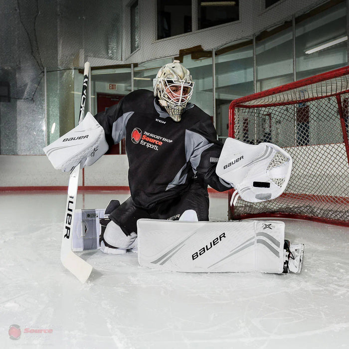 Hockey goalie in Bauer gear blocking a shot on ice, featured by The Hockey Shop