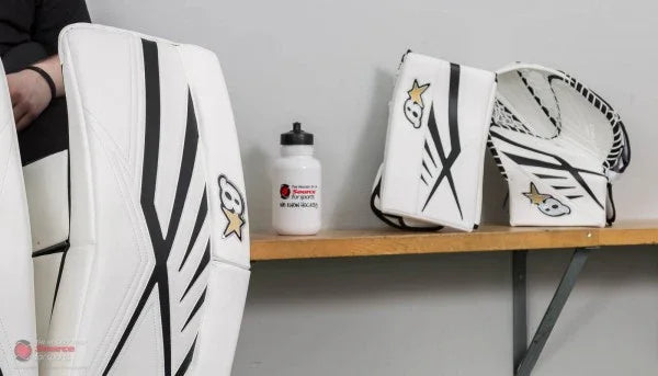 Brian's Subzero 7 white goalie leg pads, blocker, and glove on bench at The Hockey Shop