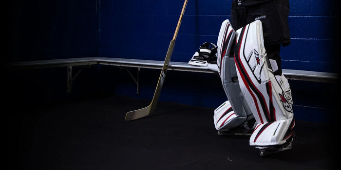 Brian's Gnetik 4 goalie leg pads and hockey stick in locker room at The Hockey Shop