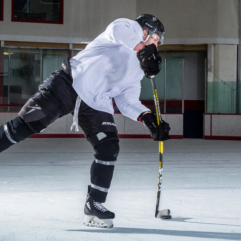 Hockey player in CCM gear shooting puck on ice rink, showcasing TheHockeyShop equipment.
