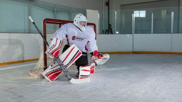 Hockey goalie in white and red CCM gear guarding the net on ice rink at The Hockey Shop