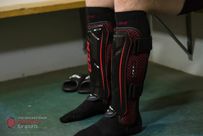 Close-up of CCM QLT hockey shin guards worn in a locker room at The Hockey Shop