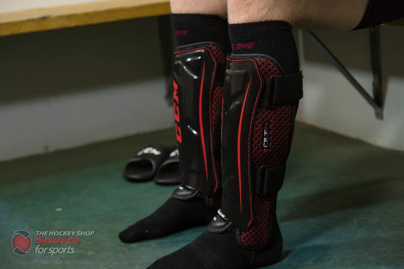 Close-up of CCM QLT hockey shin guards worn in a locker room at The Hockey Shop