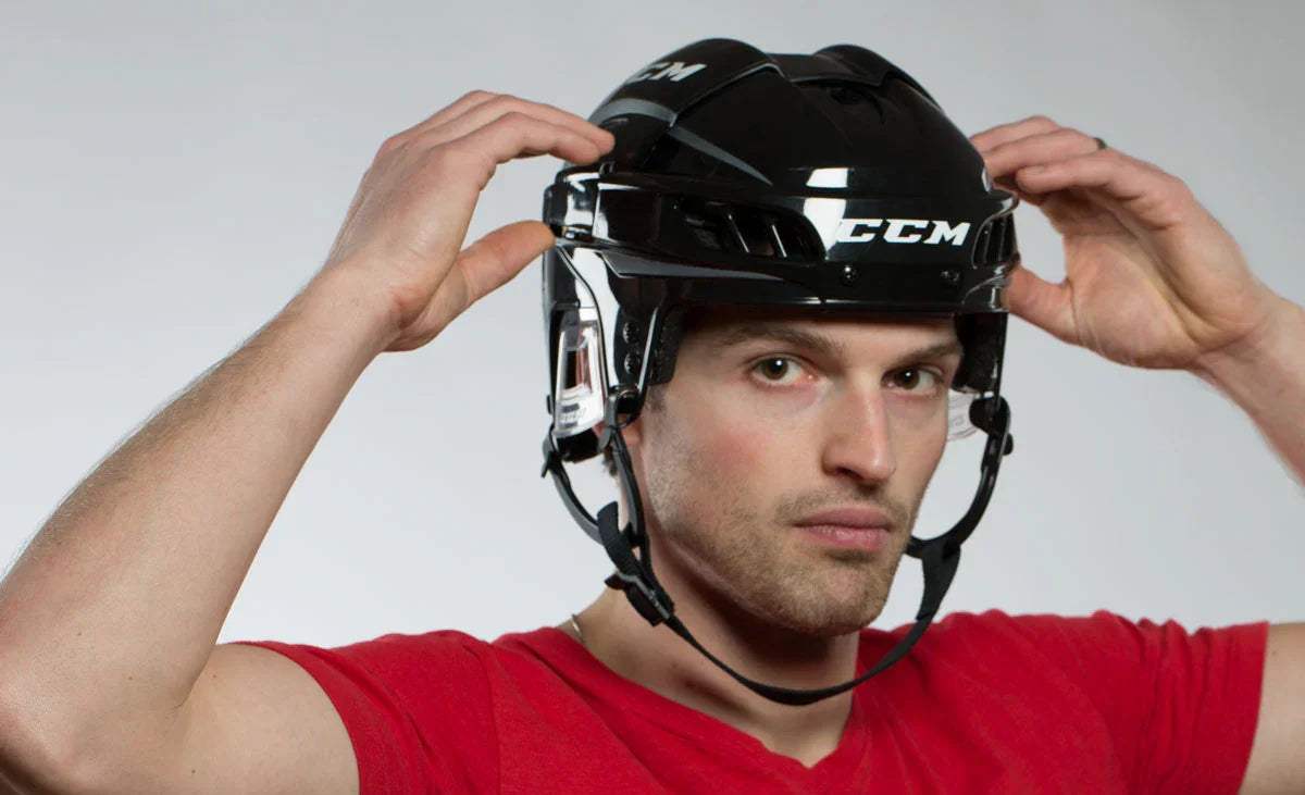 Man in red shirt adjusting CCM Fitlite hockey helmet, hockey equipment from The Hockey Shop