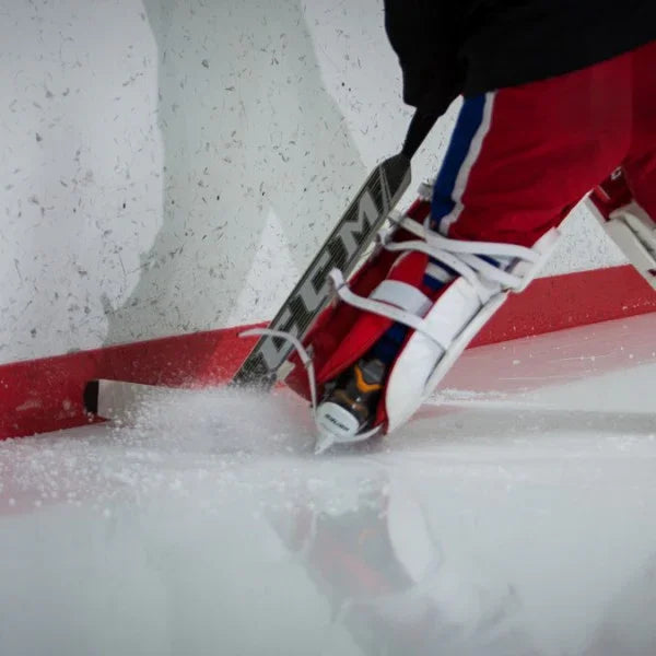CCM goalie stick in use, red goalie pads on ice near hockey net, TheHockeyShop.com