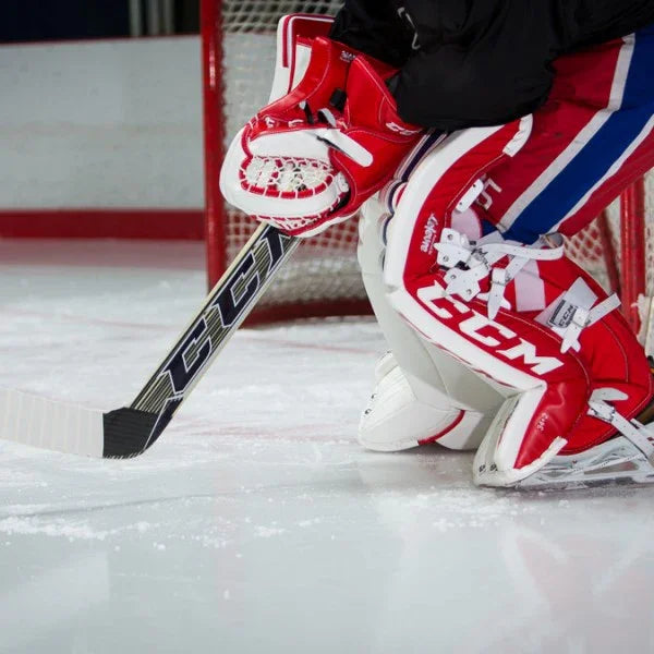 CCM goalie leg pads, blocker, and stick in red and white on ice at The Hockey Shop