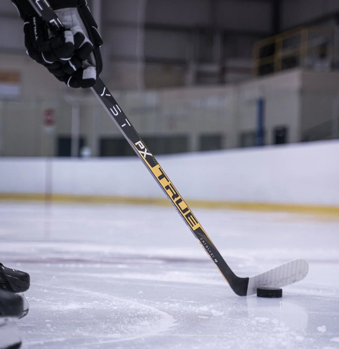 Hockey player with TRUE PX stick and puck on ice rink, TheHockeyShop.com equipment