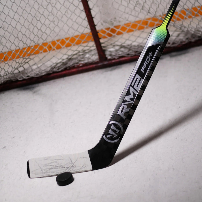 Warrior RM2 Pro+ hockey goalie stick with puck on ice in front of goal net