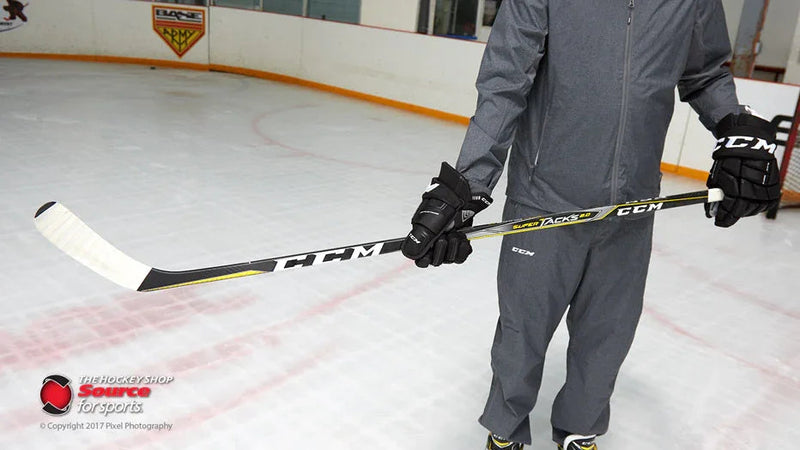 Person holding CCM Super Tacks hockey stick on ice rink at The Hockey Shop
