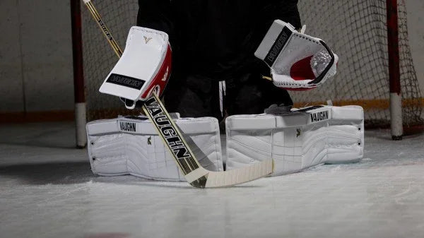 Vaughn goalie gear setup on ice rink from The Hockey Shop, featuring pads, blocker, and stick.