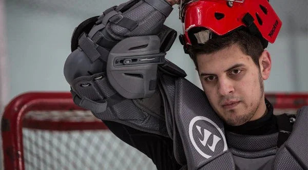 Hockey goalie in Warrior chest protector and red helmet on ice rink, TheHockeyShop.com