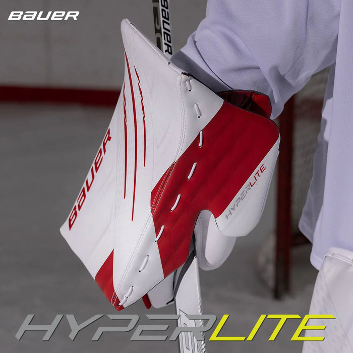 Bauer Hyperlite blocker in white and red, held by goalie on ice, The Hockey Shop equipment