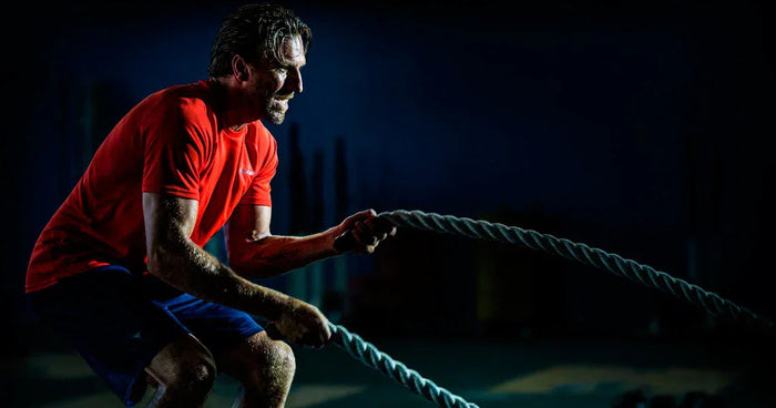 Athlete in Bauer training apparel using battle ropes in a gym, fitness and hockey gear