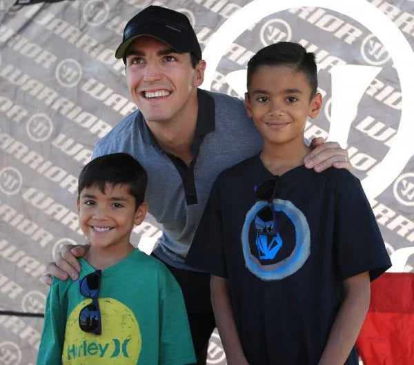 Hockey event photo of three smiling people in front of Warrior equipment banner at TheHockeyShop.com