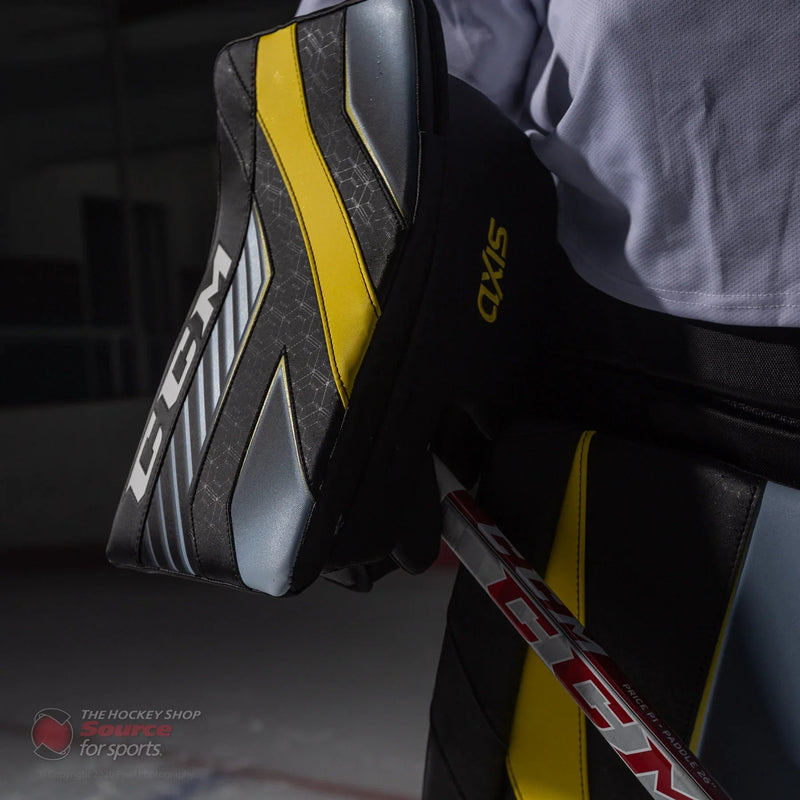 CCM Axis goalie blocker with black, yellow, and silver design on ice at The Hockey Shop