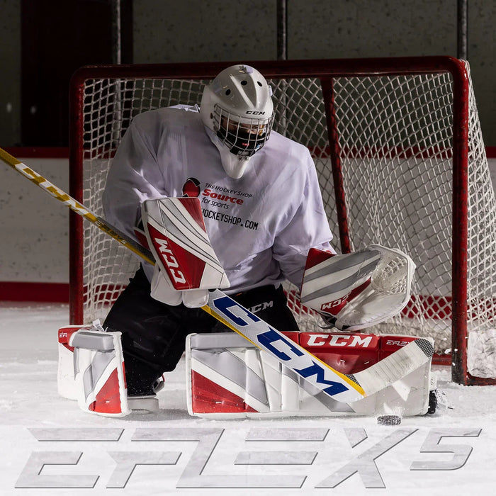CCM Eflex5 goalie stick and pads in action on ice, hockey goalie blocking puck at TheHockeyShop.com rink.