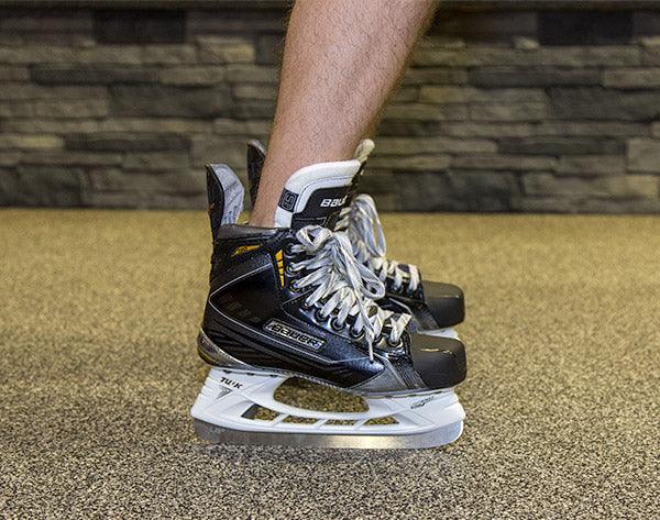 Bauer hockey skates on carpeted floor, shown upright in-store at The Hockey Shop