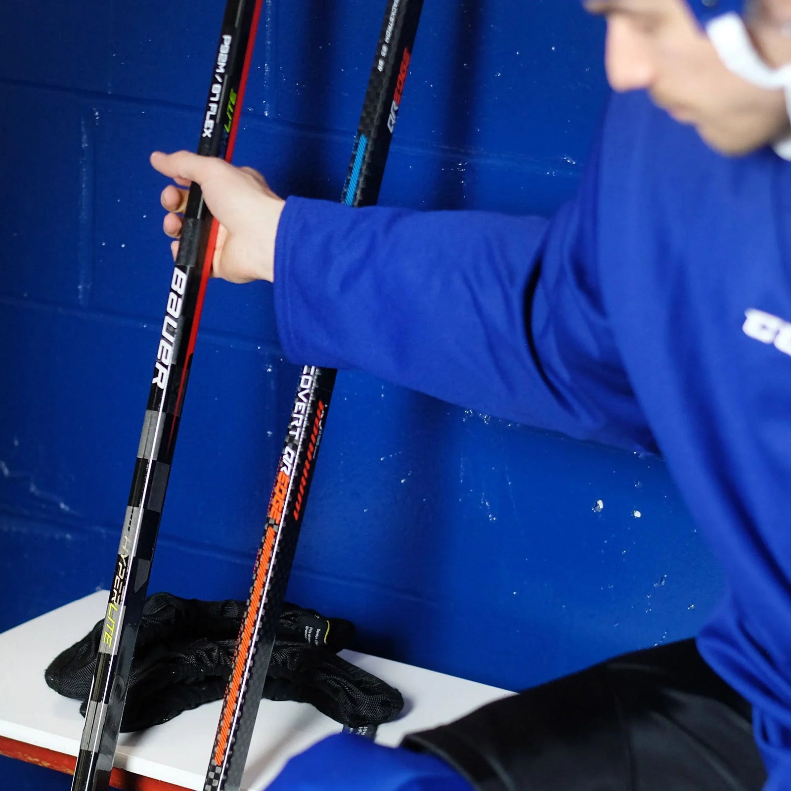 hockey player picking a hockey stick in the dressing room