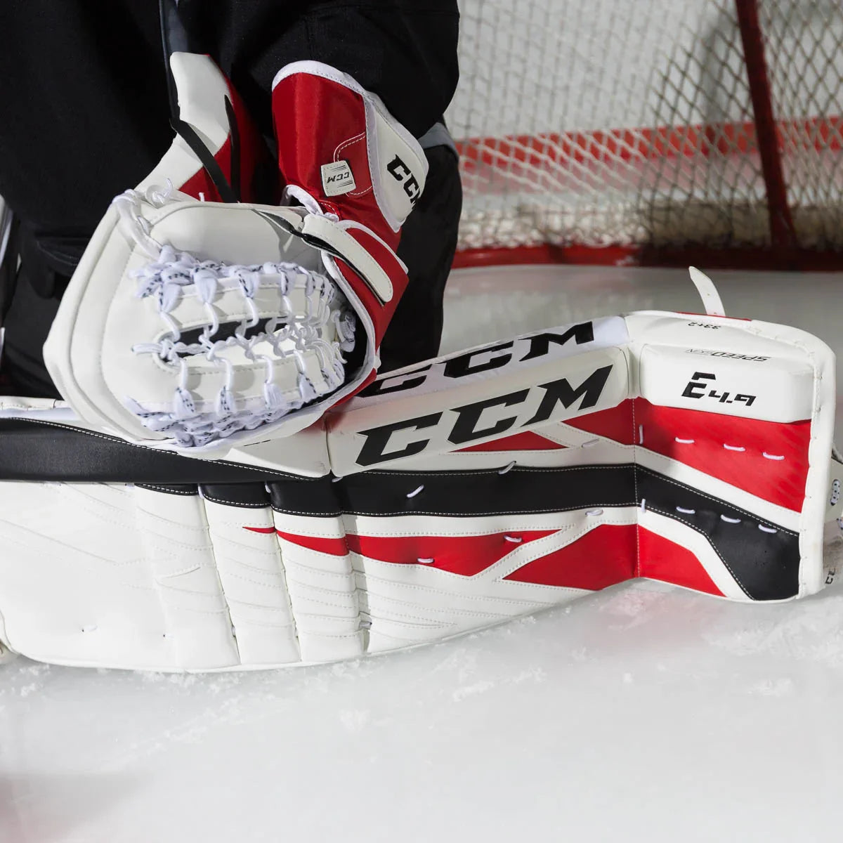 CCM E4.9 senior goalie leg pad in red, white, and black on ice at hockey rink