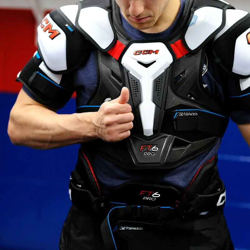 Hockey player wearing CCM Jetspeed FT6 Pro chest protector, close-up, in locker room.