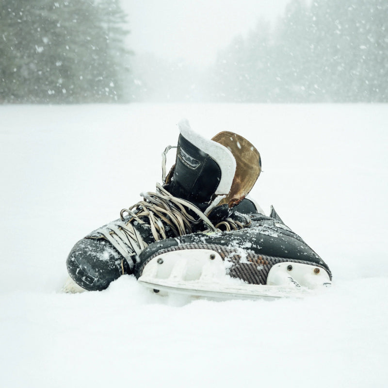 Black hockey skates covered in snow outdoors, winter scene, The Hockey Shop equipment