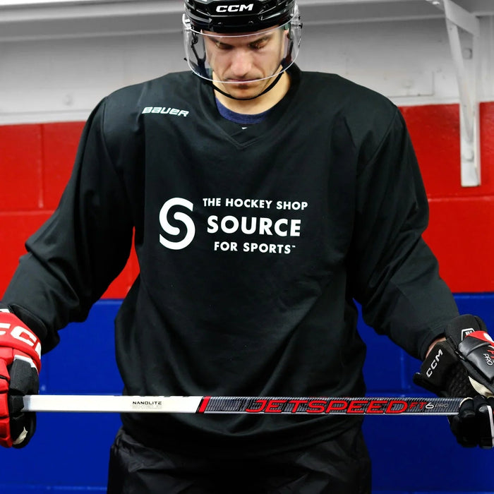 Hockey player in black The Hockey Shop jersey with CCM helmet and JetSpeed stick