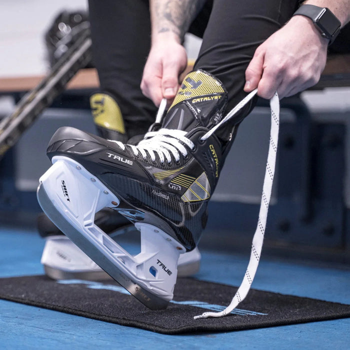 Player lacing up True Catalyst 9 ice hockey skates in locker room at The Hockey Shop