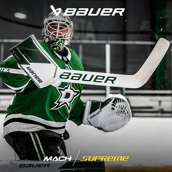 Hockey goalie in green jersey using Bauer Mach Supreme goalie equipment on the ice rink.