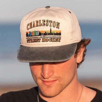 Man wearing a cap with 'Charleston Street Hockey' design against a blurred background